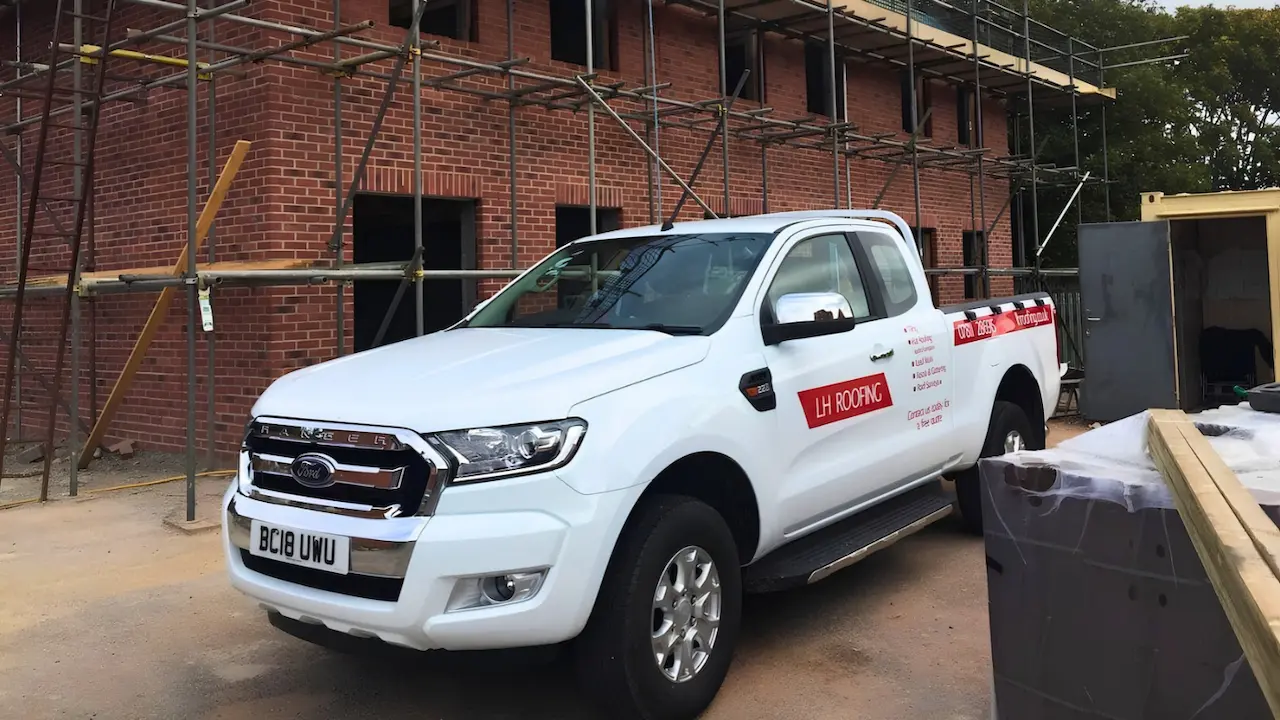 LH Roofing white truck with red logo, parked on a job site