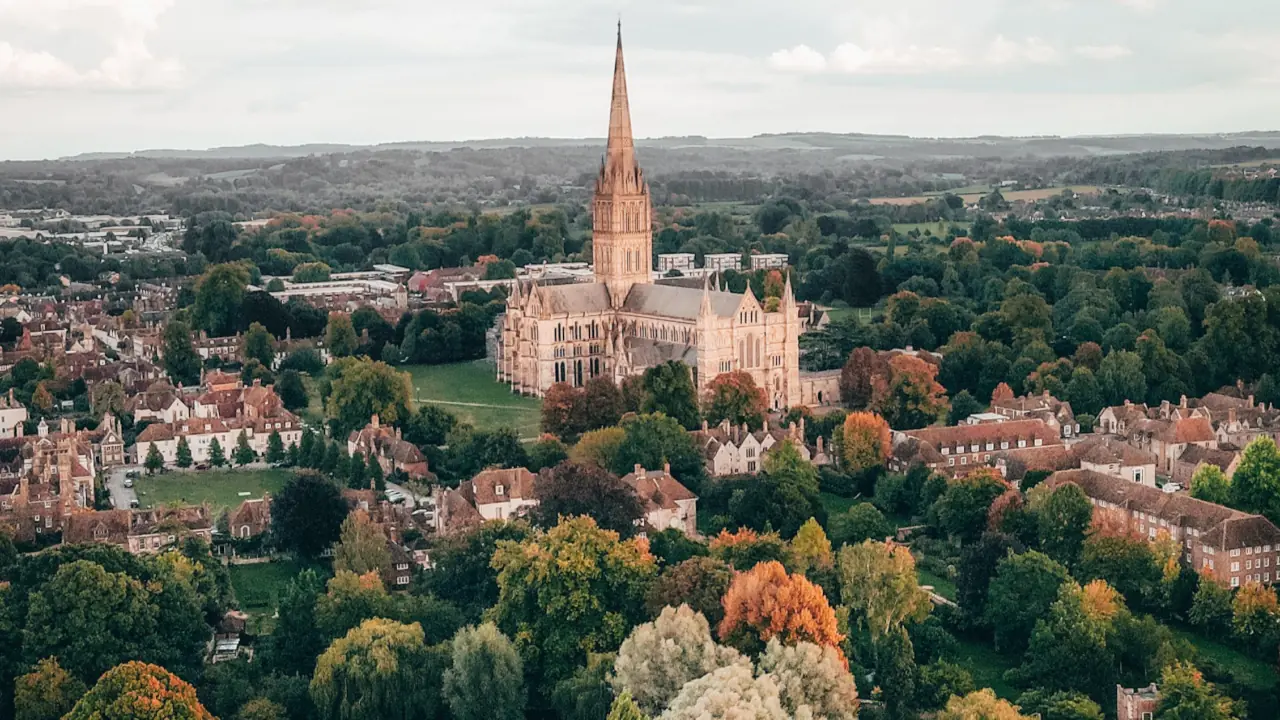 Stunning aerial shot of Salisbury Cathedral amidst lush greenery, a historic architectural marvel.